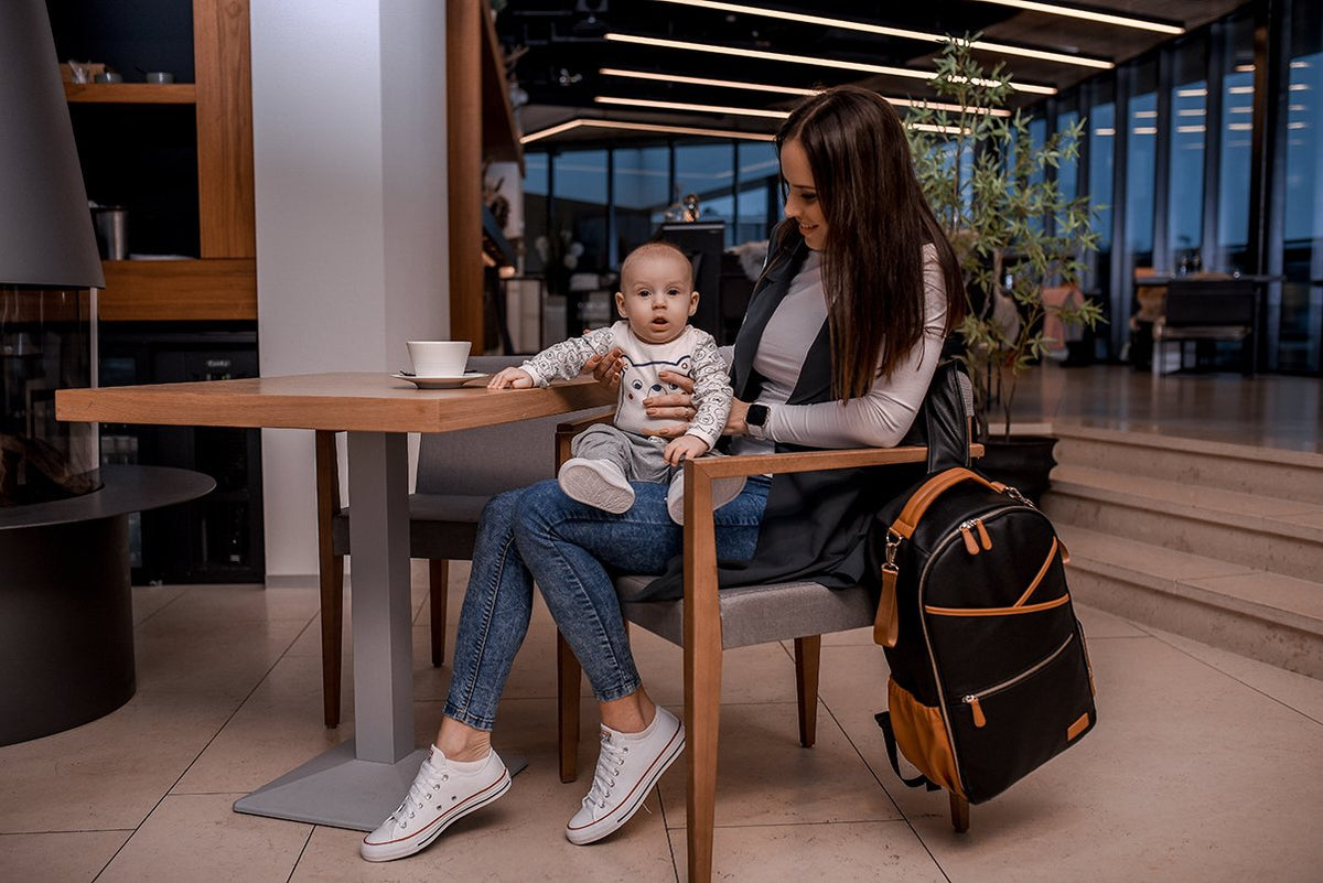 5. Woman and child at table with Ally Scandic Black Coffee diaper backpack beside them