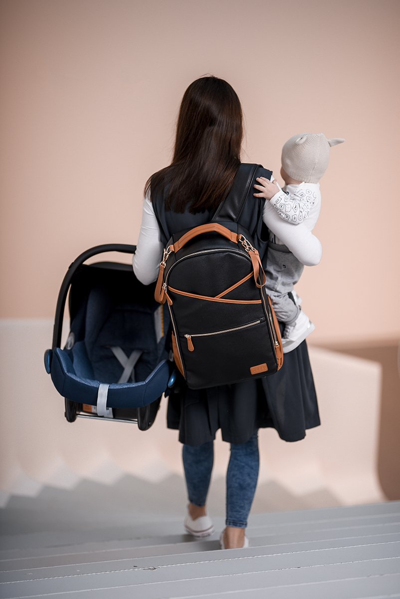 9. Woman carrying baby and car seat with Ally Scandic Black Coffee diaper backpack