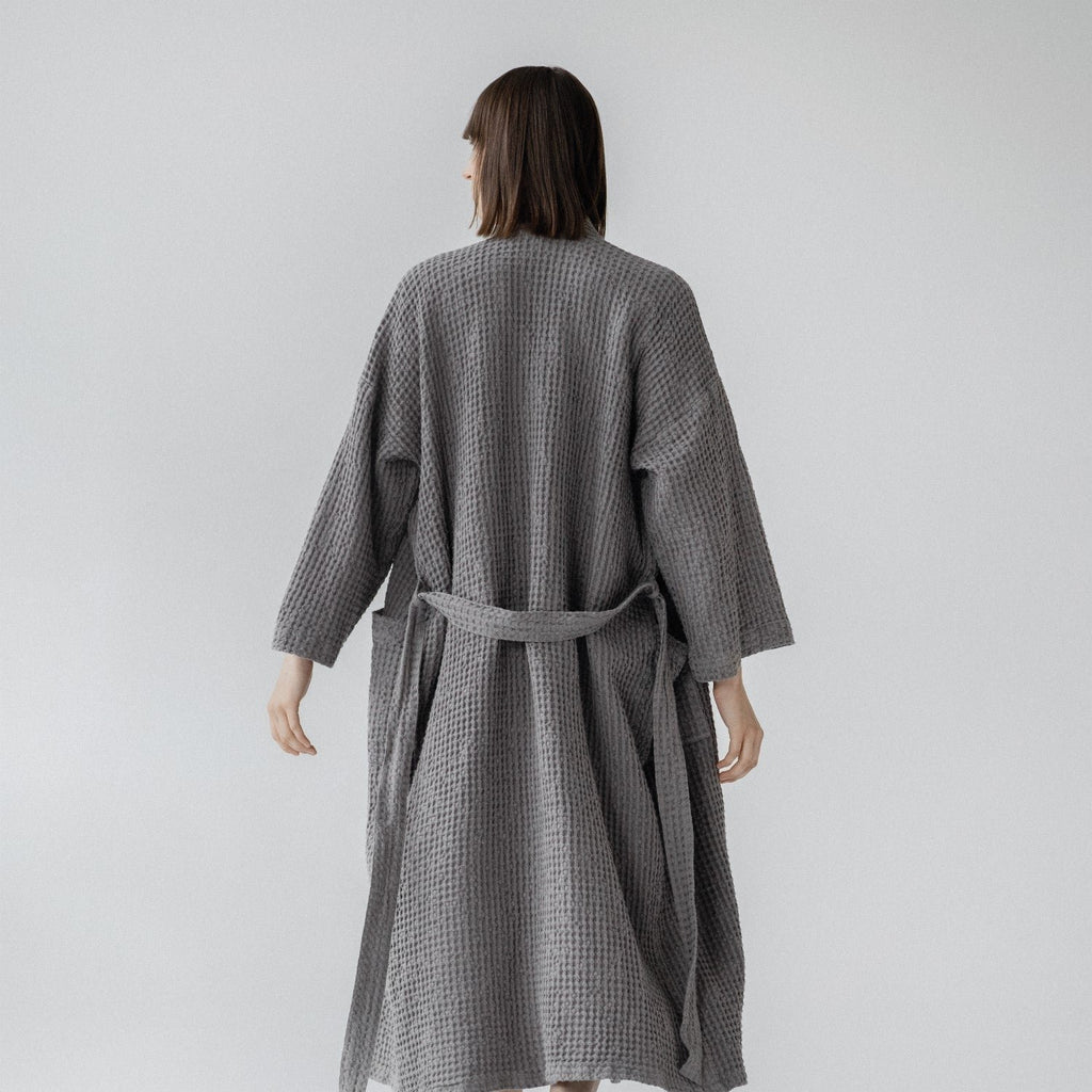 2. Woman wearing dark grey honeycomb waffle bathrobe shown from back in studio setting