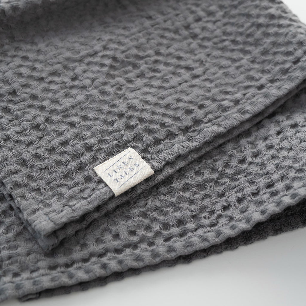 6. Dark grey honeycomb waffle towel with Linen Tales label, showcasing brand and texture