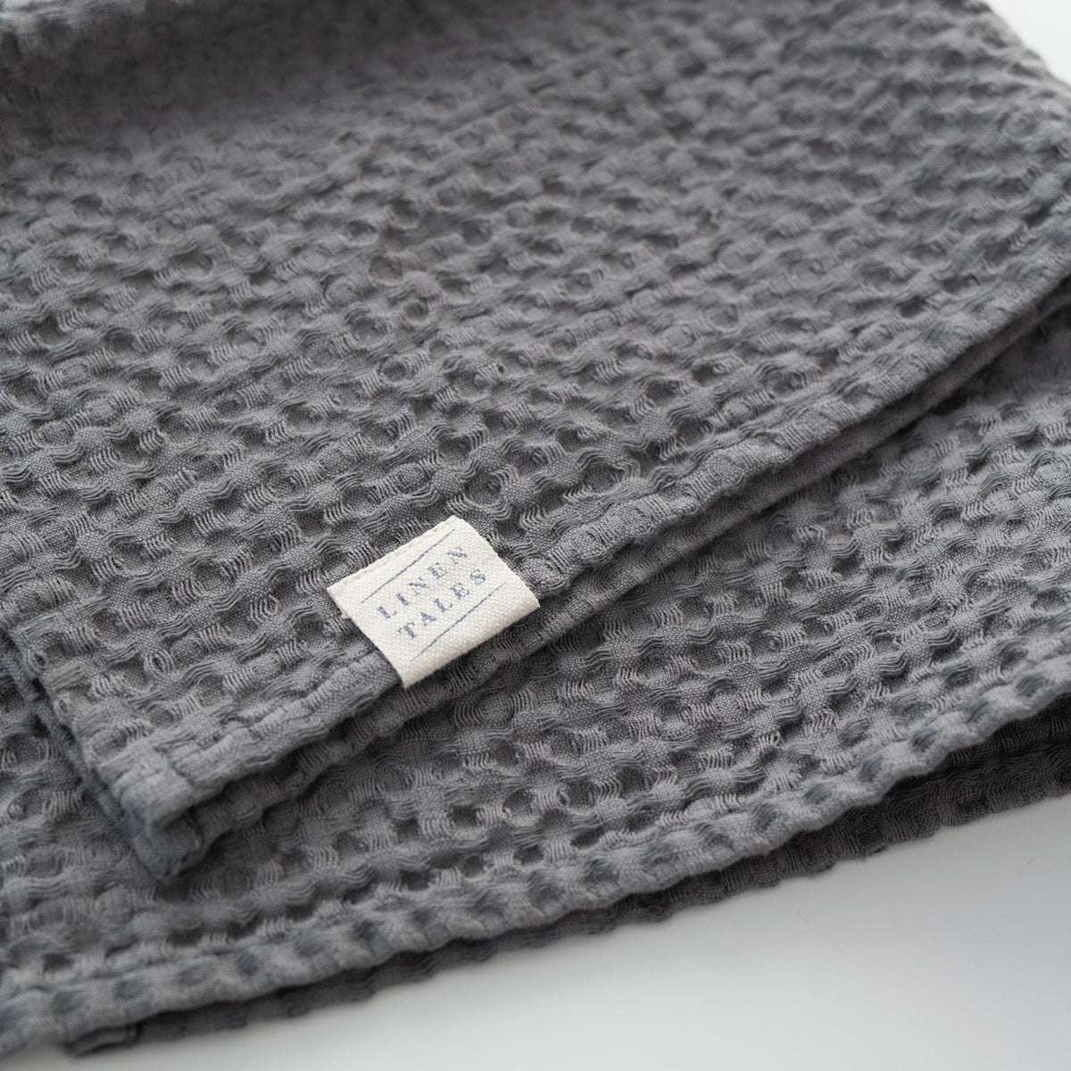 6. Dark grey honeycomb waffle towel with Linen Tales label, showcasing brand and texture