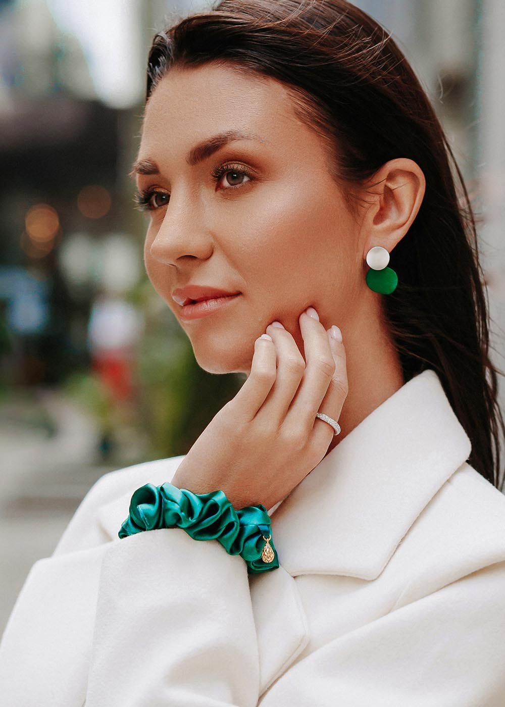 1. Woman wearing Dondella Mulberry Silk Scrunchie with crystal detail as a chic bracelet, styled with a white coat