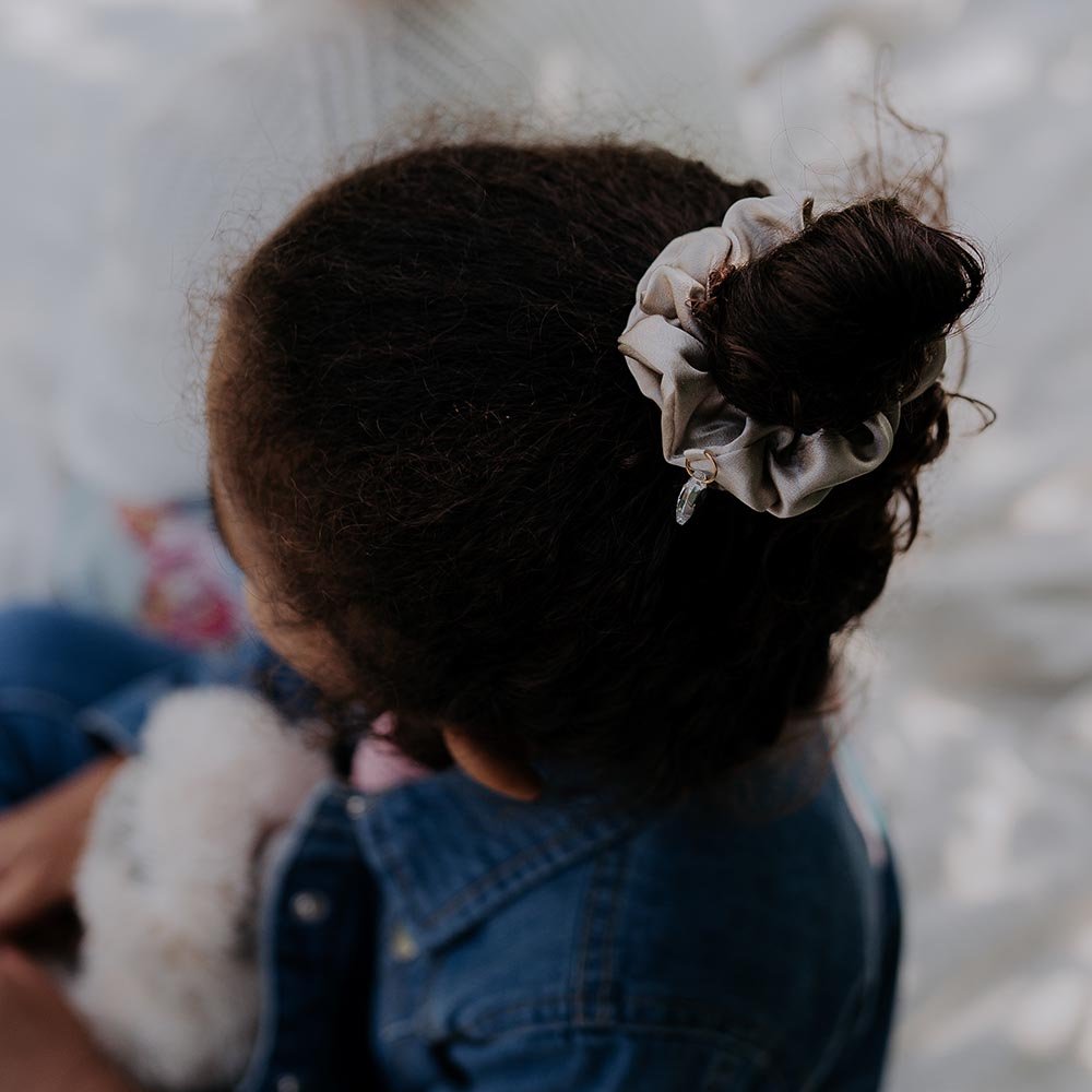 2. Child wearing Dondella luxury silk scrunchie in beige, styled in a bun