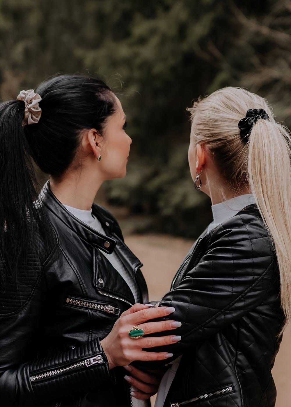 1. Two women wearing leather jackets with Dondella silk scrunchies in their hair, shown in an outdoor setting