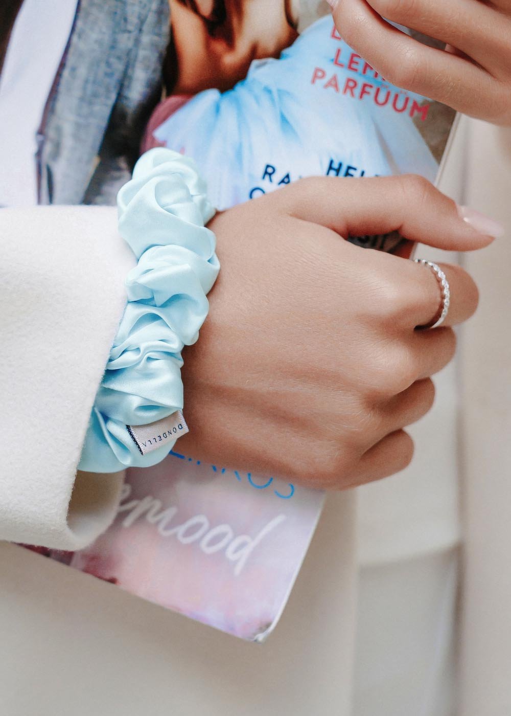 1. Woman wearing Dondella luxury silk scrunchie in aqua as a bracelet, showcasing its elegance and versatility