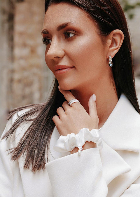 2. Woman wearing Dondella Mulberry Silk Scrunchie in Pearl as a bracelet, highlighting versatile use and luxury