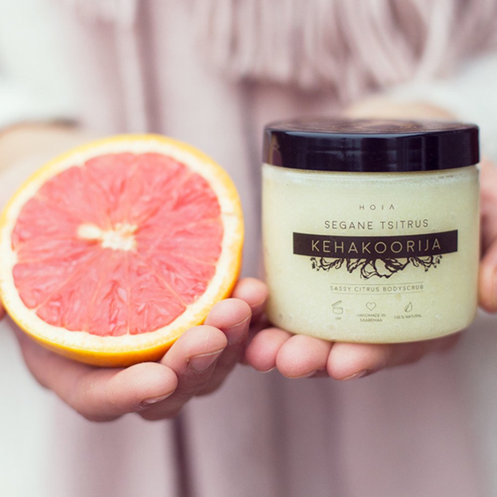 1. HOIA homespa Sassy Citrus body scrub held by a person alongside a fresh grapefruit, highlighting natural ingredients and uplifting aroma