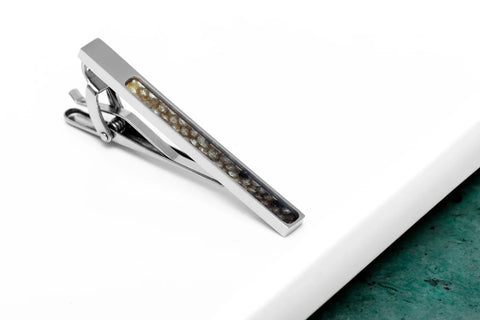 3. Close-up of black-spotted fish leather tie clip with stainless steel on white and green surface