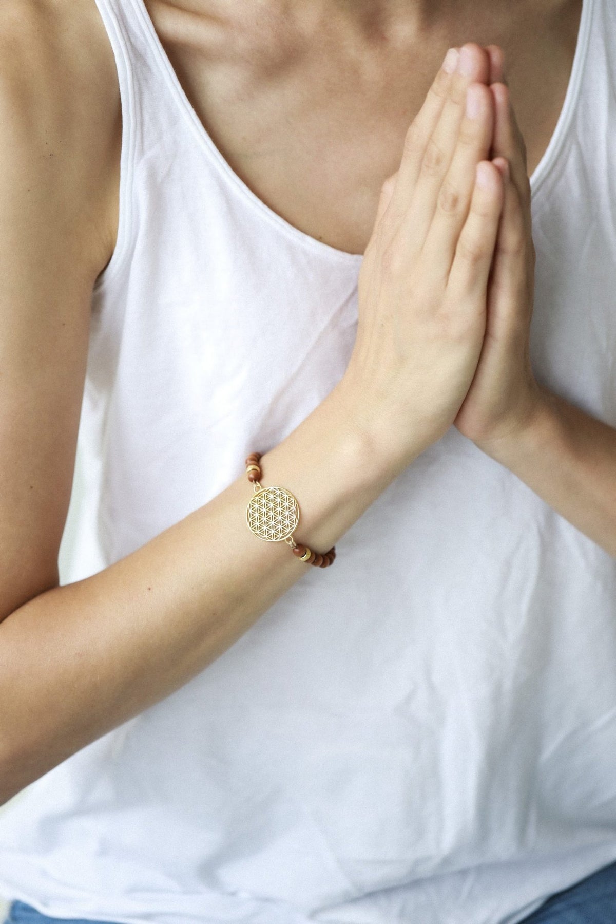 4. Close-up of woman wearing New Vintage by Kriss Flower Of Life Bracelet in sandalwood and gold, hands in prayer position