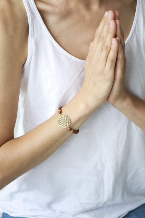 4. Close-up of woman wearing New Vintage by Kriss Flower Of Life Bracelet in sandalwood and gold, hands in prayer position