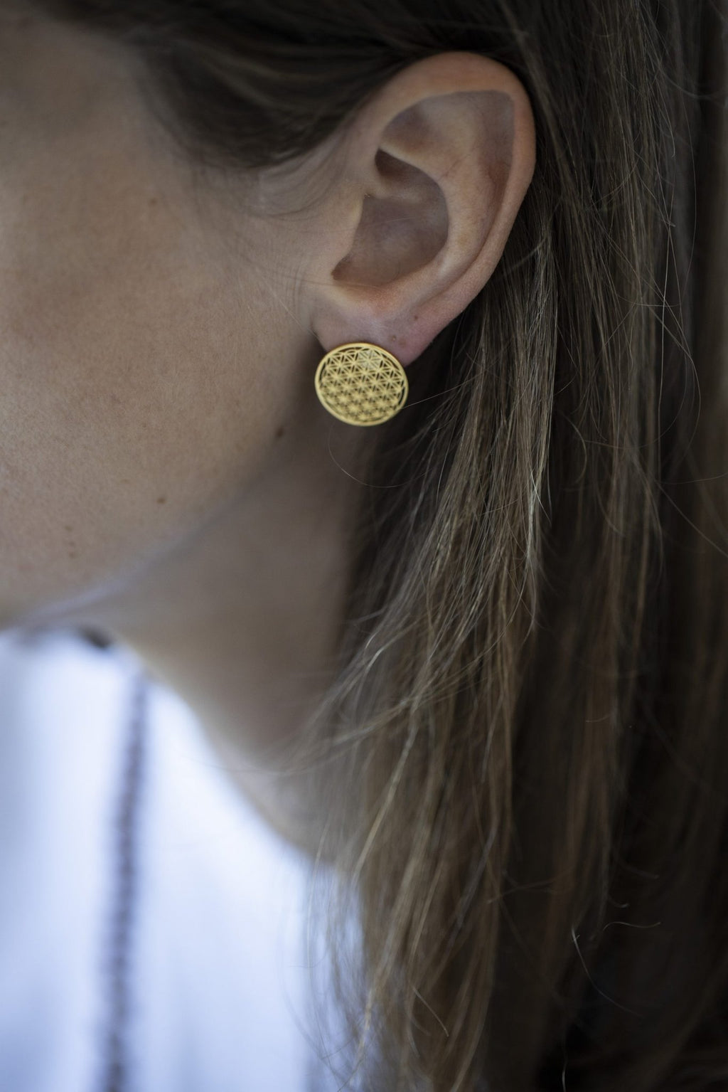 3. Close-up of New Vintage by Kriss Flower Of Life gold stud earring worn by a woman