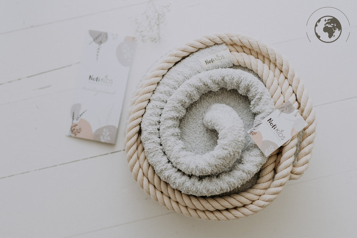 4. Flat lay of ice grey bouclé swing with cotton rope and Nofi KIDS tag on white floor