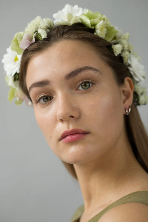 1. Woman wearing Alas Upcycled Earrings by Lentsius, styled with a floral crown, showcasing sustainable stainless steel design