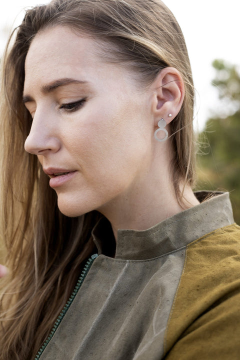 2. Close-up of woman wearing Lentsius Arc silver earrings, highlighting brushed stainless steel finish