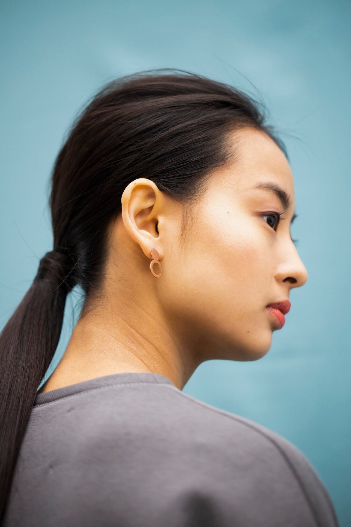 5. Side view of woman wearing Lentsius Arc rose gold earrings, highlighting eco-conscious design