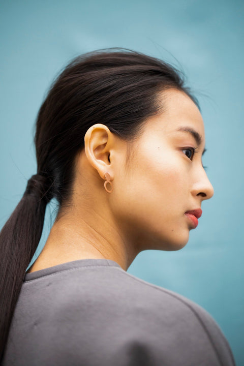 5. Side view of woman wearing Lentsius Arc rose gold earrings, highlighting eco-conscious design