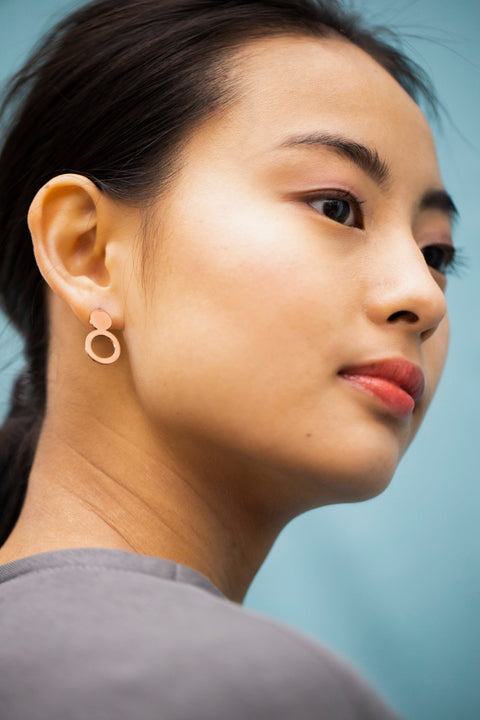 2. Close-up of woman wearing Lentsius Arc rose gold earrings, highlighting unique design and brushed finish