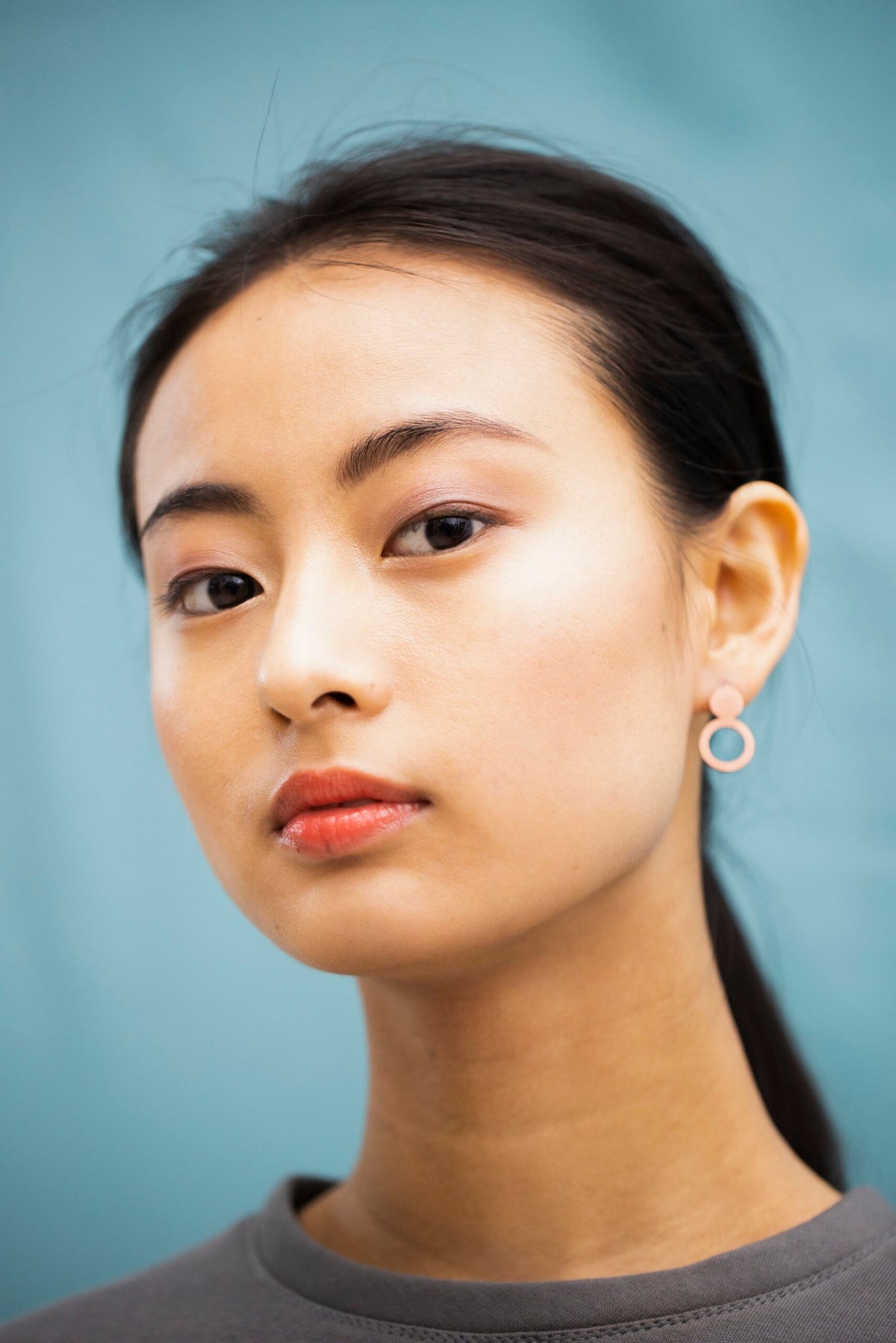 4. Woman wearing Lentsius Arc rose gold earrings, side profile showing stainless steel construction
