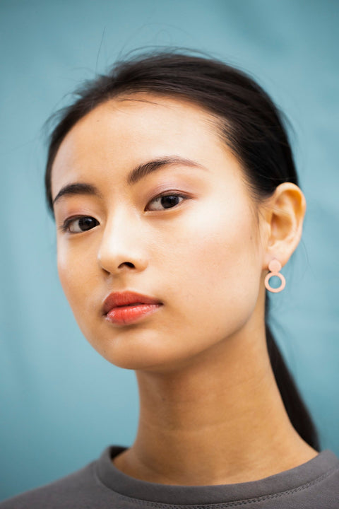 4. Woman wearing Lentsius Arc rose gold earrings, side profile showing stainless steel construction