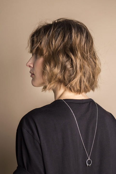 1. Woman wearing Lentsius stainless steel necklace with unique pendant, shown from the back