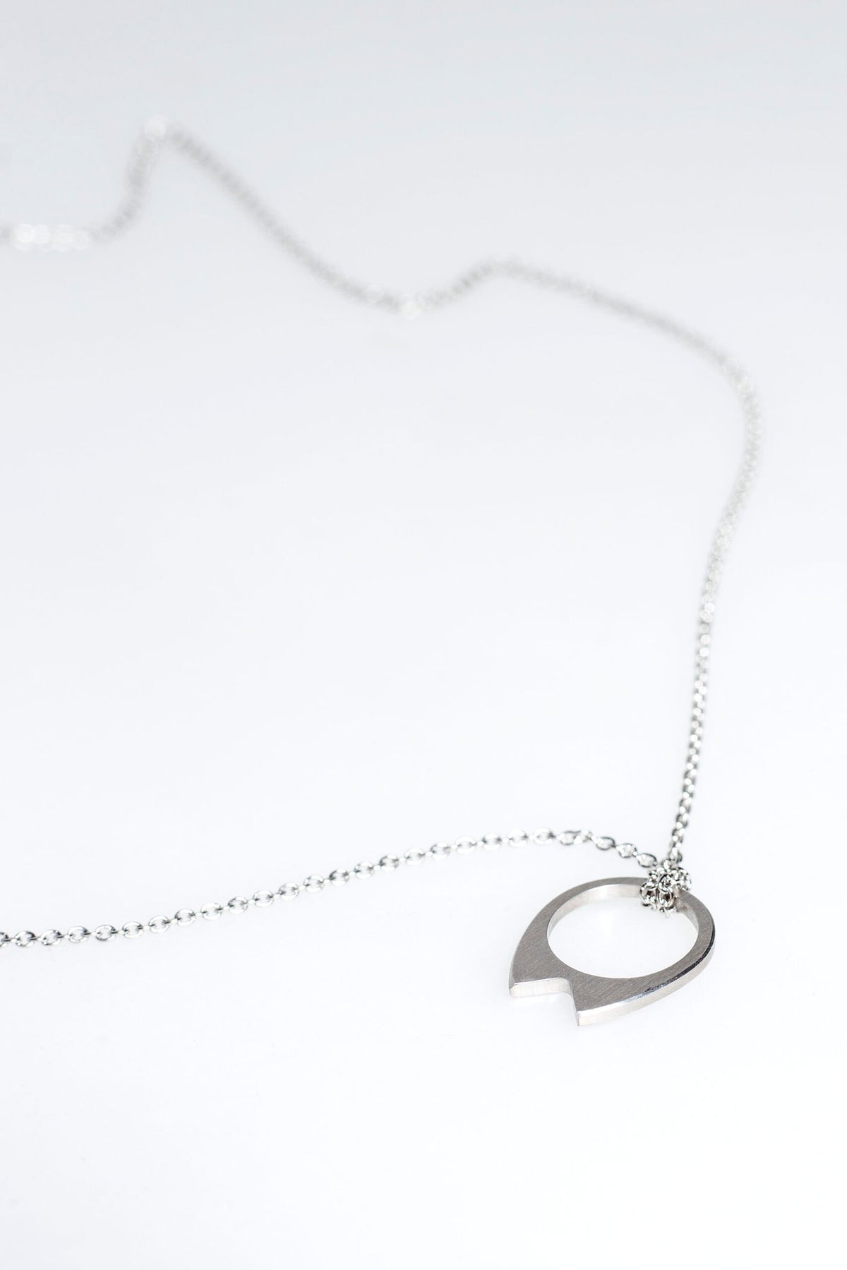 2. Close-up of Lentsius stainless steel necklace with circular pendant on white background