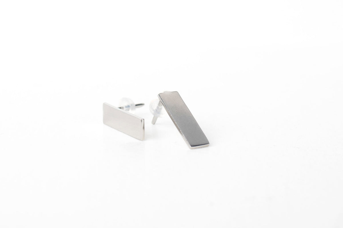 3. Studio shot of Lentsius Corner silver earrings, featuring brushed stainless steel and silicone stoppers