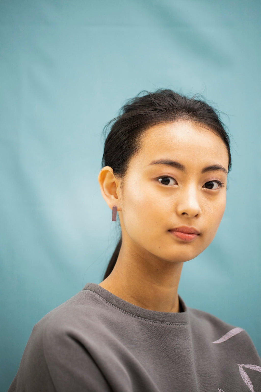 1. Woman wearing Lentsius Corner Purple earrings, showcasing sustainable design in lifestyle setting