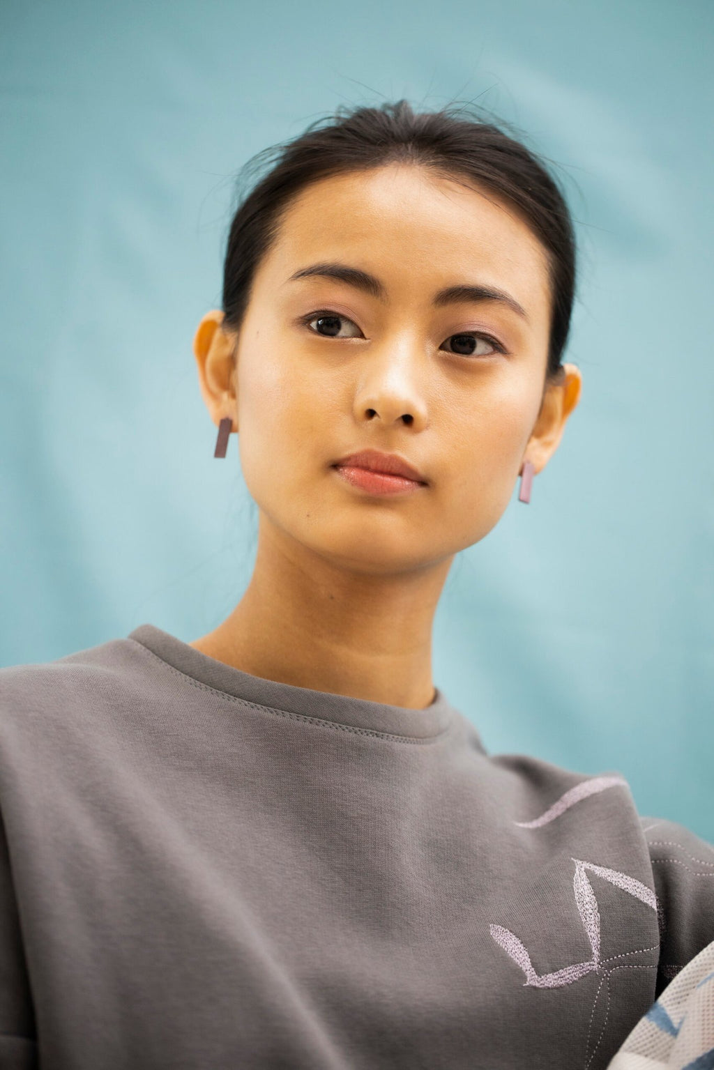 3. Woman modeling Lentsius Corner Purple earrings, emphasizing elegant design and sustainable materials