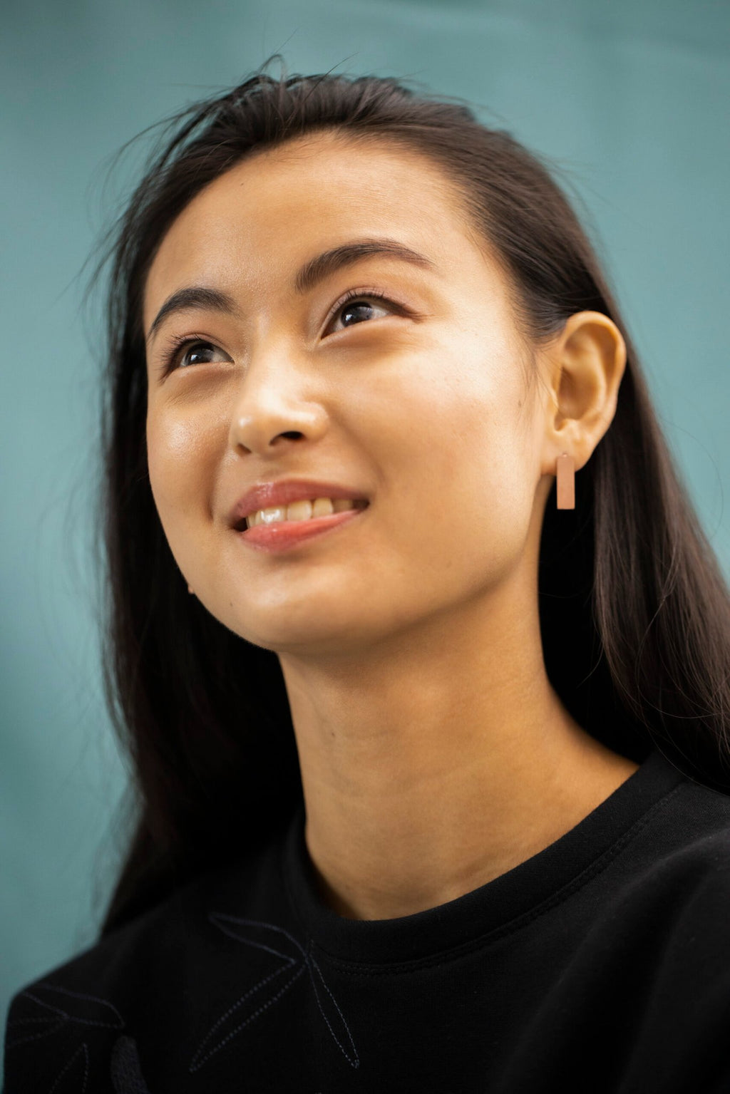 6. Woman smiling with Lentsius Corner rose gold earrings, showcasing elegant design