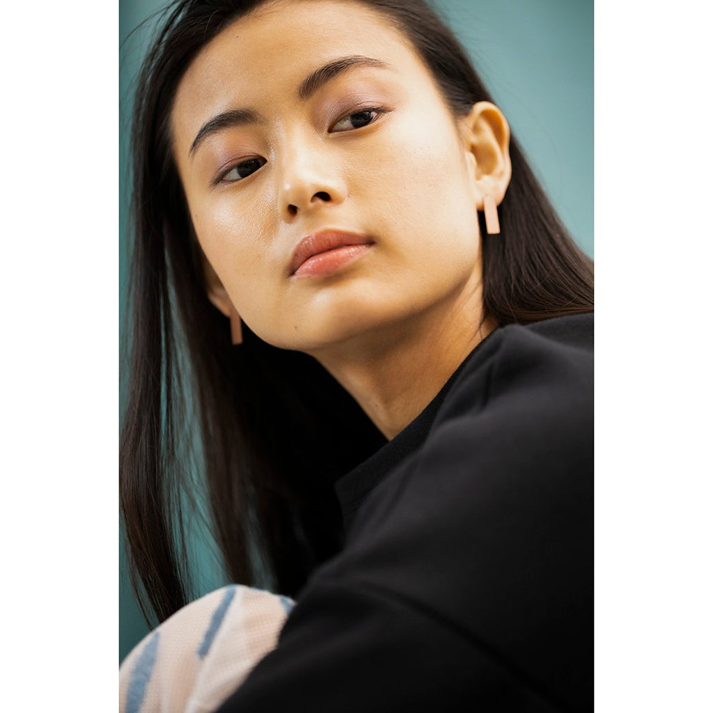 1. Woman wearing Lentsius Corner rose gold earrings, showcasing sustainable design in lifestyle setting