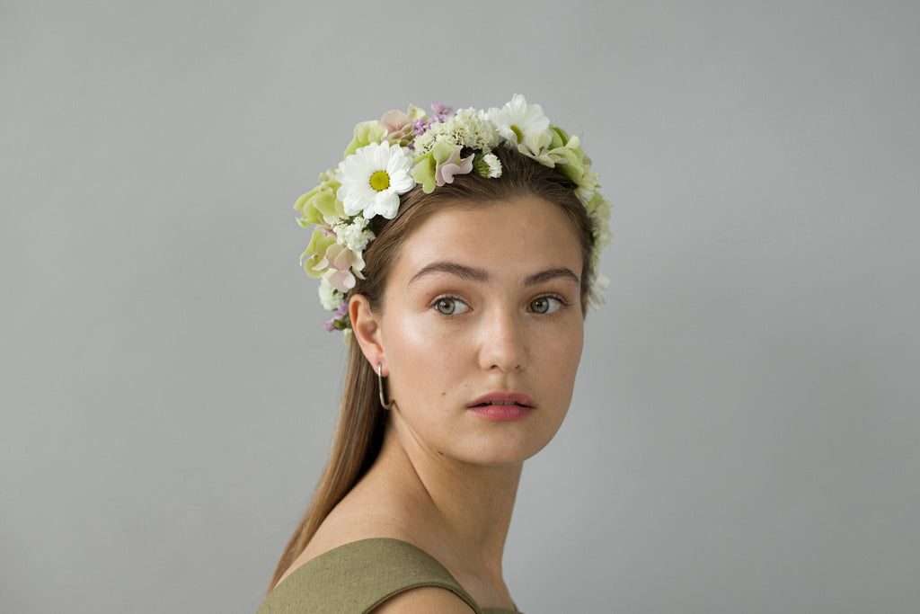 1. Woman wearing Lentsius Curvi earrings with floral headpiece, showcasing Scandinavian design
