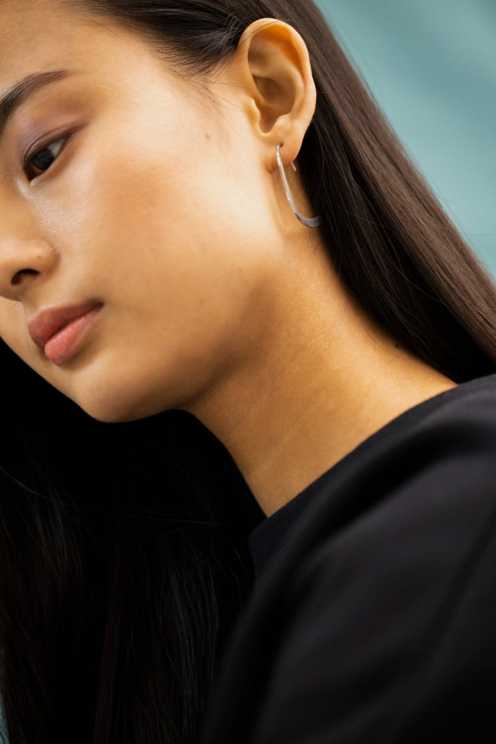 6. Side view of woman wearing Lentsius Curvi earrings, showcasing hypoallergenic stainless steel