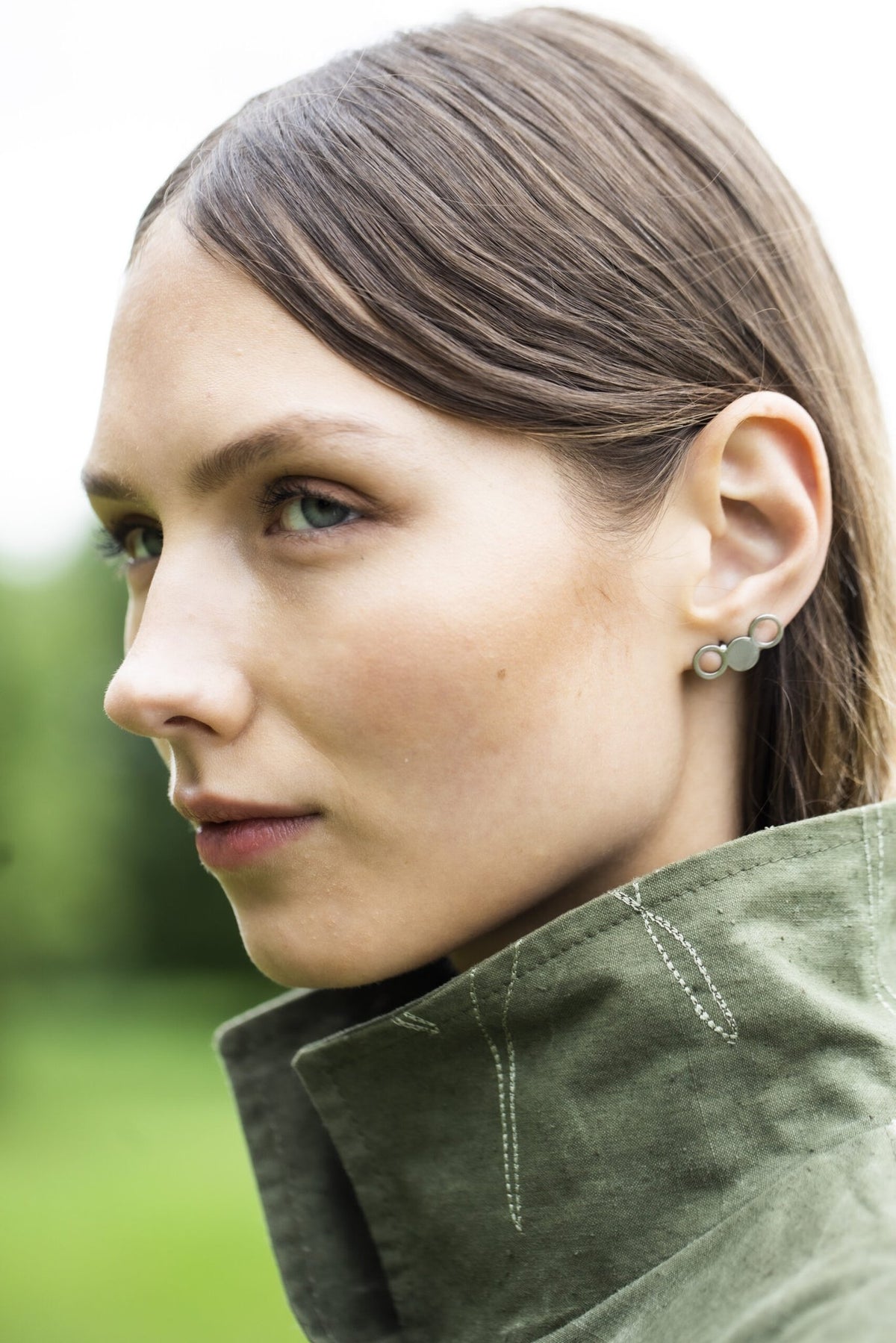 1. Woman wearing Lentsius Silva stainless steel earrings in outdoor setting