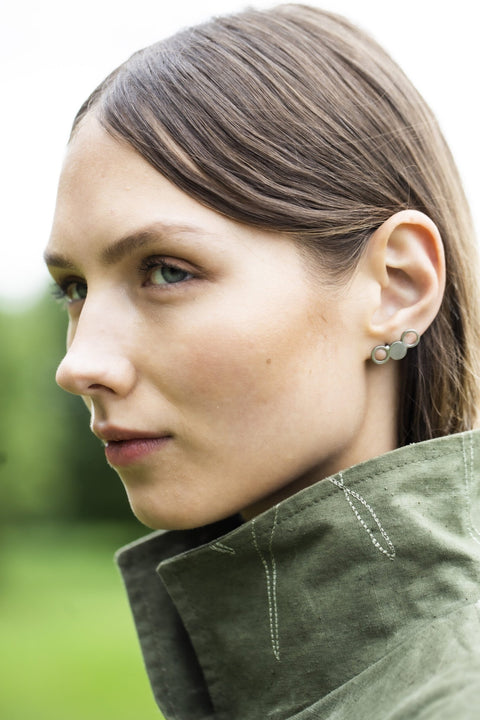 1. Woman wearing Lentsius Silva stainless steel earrings in outdoor setting