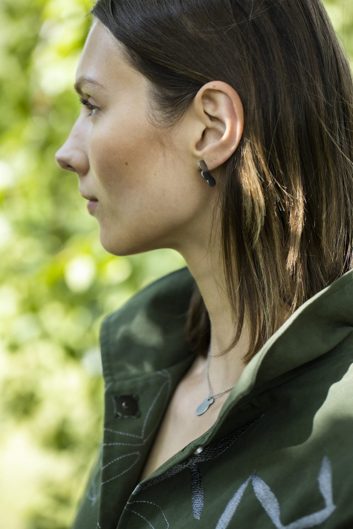 2. Side view of woman wearing Ursa necklace by Lentsius with green jacket