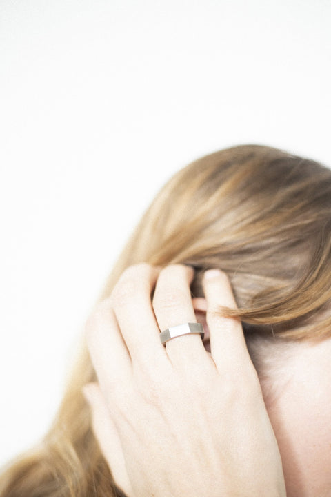 5. Close-up of woman adjusting hair, wearing Lentsius Plico ring in stainless steel