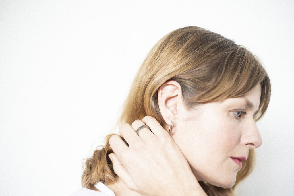 6. Woman touching hair, wearing Lentsius Plico ring in stainless steel, showcasing Scandinavian design
