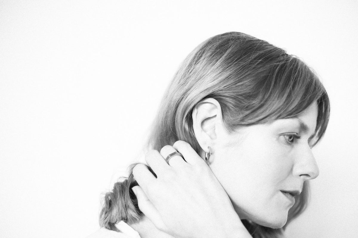 7. Woman with side profile, wearing Lentsius Plico ring in stainless steel, highlighting eco-friendly elegance