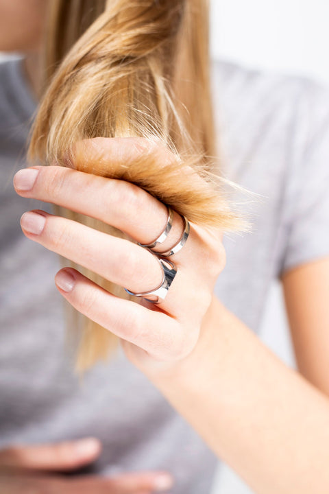 5. Woman playing with hair while wearing Lentsius Versus ring, showing modern style