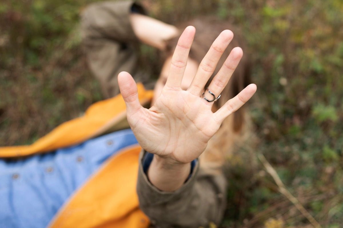 3. Woman lying in grass with Lentsius Versus ring, emphasizing eco-friendly craftsmanship