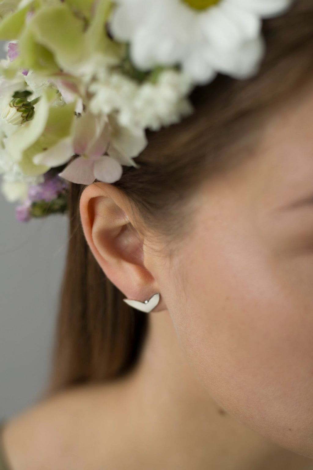 3. Close-up of Lentsius Vola silver earring on woman's ear with floral headpiece, showing polished finish