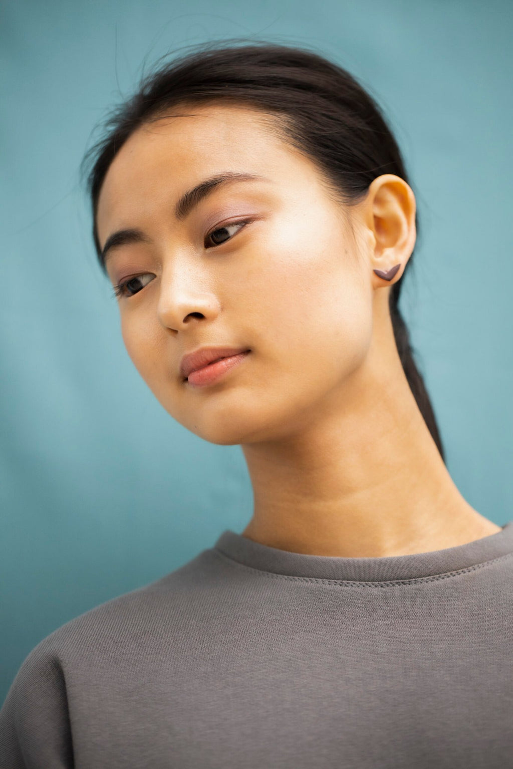 1. Woman wearing Lentsius Vola purple earrings, showcasing Scandinavian style in a lifestyle setting