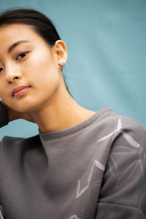 5. Woman with hand on neck wearing Lentsius Vola purple earrings, showcasing innovative design