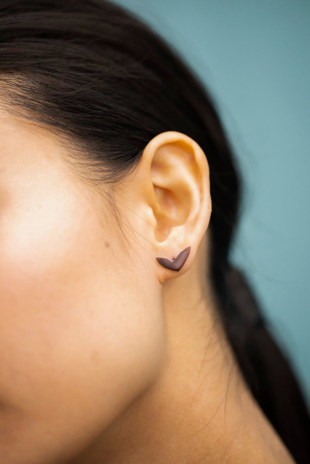 6. Close-up of Lentsius Vola purple earring on woman's ear, highlighting polished PVD coating