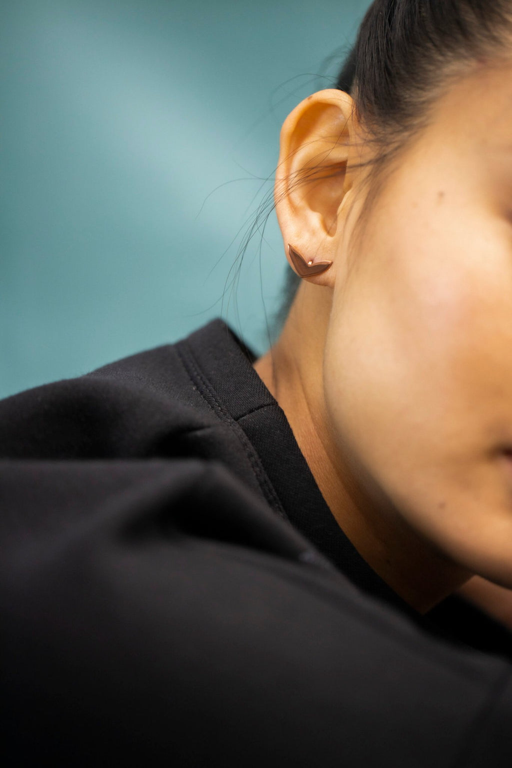 8. Close-up of Lentsius Vola rose gold earring on woman's ear, showcasing polished finish