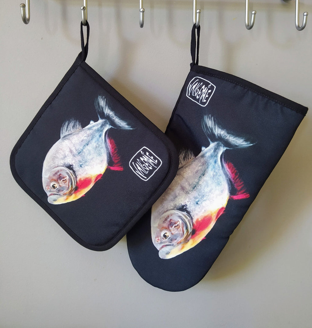 6. Pot holder and oven mitt with fish painting inspired by Goya, hanging on hooks, featuring dark background and artist's signature
