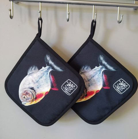 4. Pair of pot holders with fish painting inspired by Goya, hanging on hooks, featuring dark background and artist's signature