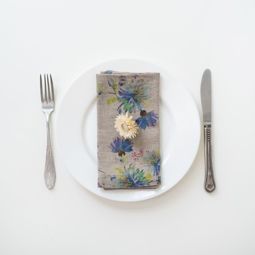 11. Floral linen napkin on a white plate with a decorative flower, accompanied by fork and knife