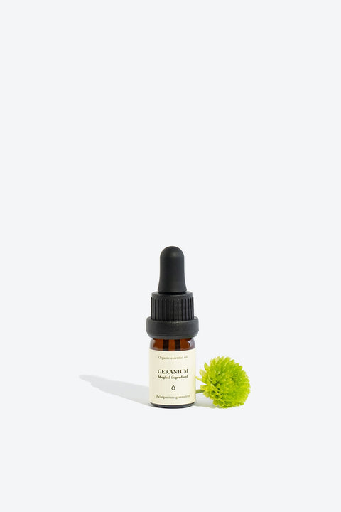 2. Smells Like Spells GERANIUM Essential Oil in 5 ml glass bottle with green flower, studio setting