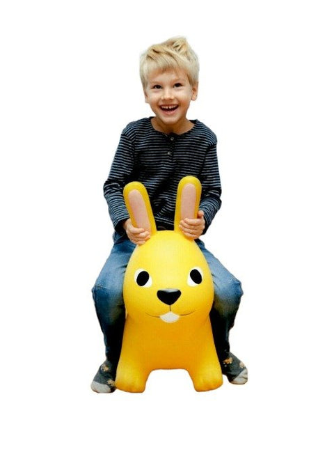 1. Smiling child sitting on yellow bunny hopper toy against a white background